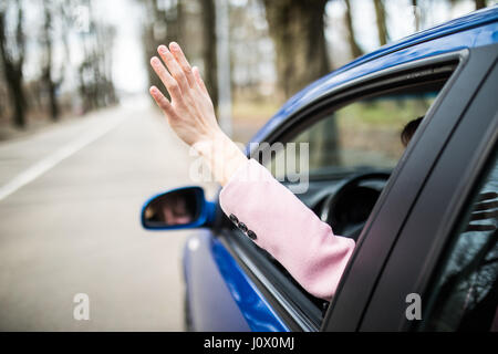 Donna sticking braccio fuori la finestra auto su roadtrip. Foto Stock
