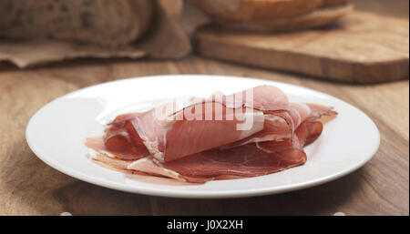 Italian speck prosciutto su una piastra sulla tavola di legno Foto Stock