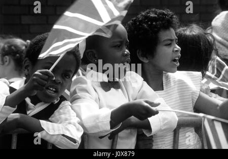 Bambini locali sventolando union jack flag per il Principe Carlo in visita a Handsworth, Birmingham Regno Unito Giugno 1986 Foto Stock