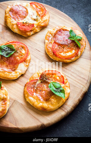 Italian mini pizza con salame formaggio pomodori e basilico per snack Foto Stock