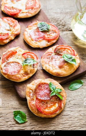 Italian mini pizza con salame formaggio pomodori e basilico per snack Foto Stock