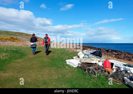 Walkers pass raccolti detriti marini da un recente spiaggia pulita fino in Fife sentiero costiero tra Crail a Anstruther Foto Stock