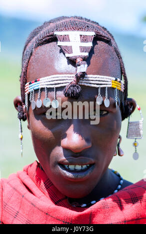 Ritratto di un giovane guerriero maasai tanzaniano in testa tribale Gioielli di perle e ornamenti d'argento e tradizionale rosso Shuka Robe. Foto Stock