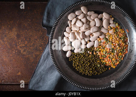 Placer fagioli verdi e bianchi, le lenticchie in una ciotola di legno e un tovagliolo in orizzontale Foto Stock