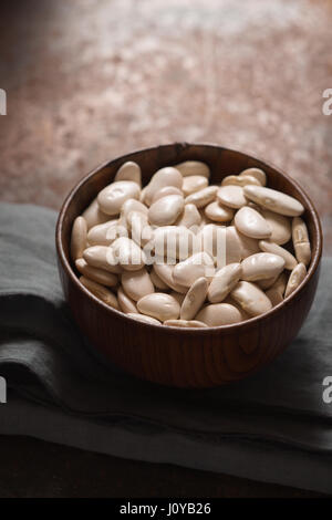 Grandi di fagioli bianchi in una ciotola di legno vista laterale verticale Foto Stock