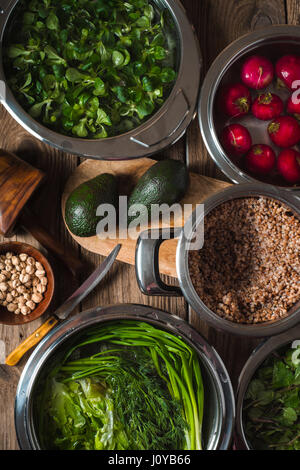 Il grano saraceno in una pentola, erba verde in acqua e di avocado sul tavolo in verticale Foto Stock