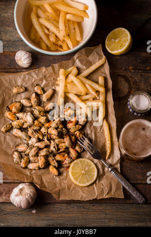 Cozze con limoni e patatine fritte sul metallo verticale di sfondo Foto Stock