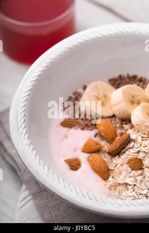 Yogurt alla frutta con diversi condimenti sul bianco tavolo in legno Foto Stock