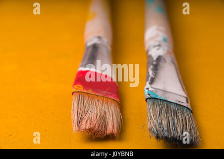 Due pennelli per dipingere su una tabella di colore giallo Foto Stock