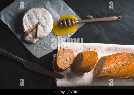 Formaggio Brie, pezzi di baguette, miele su pergamena Foto Stock