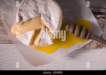 Formaggio Brie, fetta, miele su pergamena e su un supporto Foto Stock