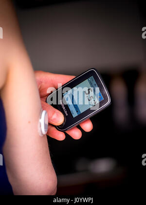 Una donna con il diabete di Tipo 1 utilizzando un flash monitor glucosio chiamato Freestyle Libre realizzato da Abbott. Foto Stock
