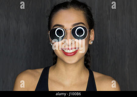 Ritratto di una giovane donna con occhiali da sole, ridendo Foto Stock