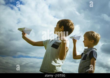 Ragazzi piccoli con piani di carta contro il cielo blu Foto Stock