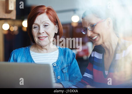 Felice femmine mature a guardare i video online in laptop Foto Stock