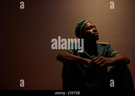 Giovani afro-americani seduta facchino dalla parete di hotel Foto Stock