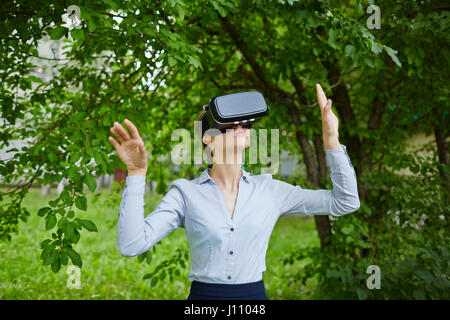 Ritratto di giovane donna che indossa gli occhiali VR nella foresta vivendo la realtà aumentata effetti Foto Stock