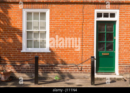 Verde britannico vittoriano porta anteriore e finestra bianca su una rossa muro di mattoni Foto Stock