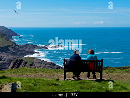 Giovane seduto su un banco di lavoro, che guarda al mare, Penwith, Cornwall, England Regno Unito Foto Stock