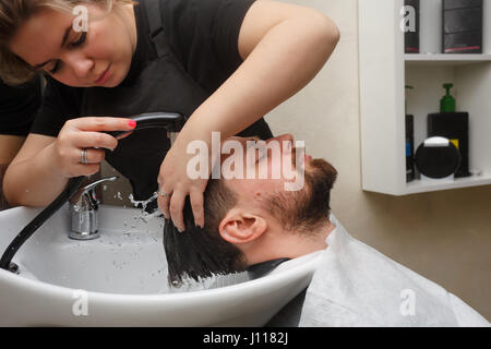 Parrucchiere professionale facendo taglio maschile di capelli. Il parrucchiere lava la testa del client. Salone di bellezza. Bellezza maschile. Il client è un hipster. Foto Stock