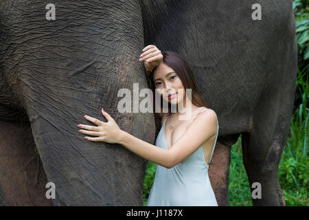 Donna appoggiata contro un elefante, Tegallalang, Bali, Indonesia Foto Stock