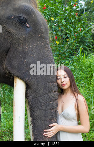 Donna appoggiata contro elephant con gli occhi chiusi, Tegallalang, Bali, Indonesia Foto Stock