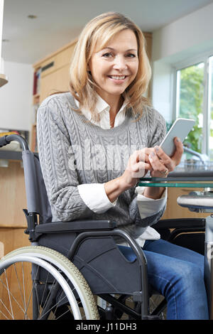 Donna disabile in carrozzella sms sul cellulare a casa Foto Stock