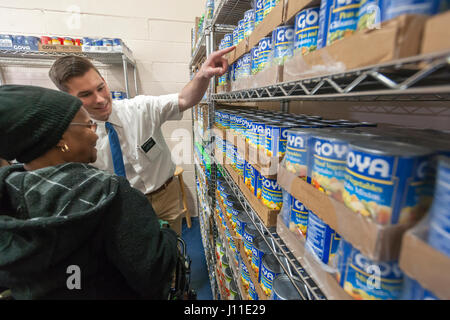 Un missionario mormone assiste un client presso la Catholic Charities Bronx della distribuzione alimentare Center di New York il Giovedì Santo, 13 aprile 2017. Il centro di distribuzione, rifornito con generose donazioni da Goya alimenti e altre società elabora 513,000 libbre di cibo al mese, distribuire direttamente ai bisognosi e attraverso una rete di interfaith gli alimenti riposterie in tutto il Bronx e Upper Manhattan. Catholic Charities sta celebrando il 100 anniversario quest'anno. (© Richard B. Levine) Foto Stock