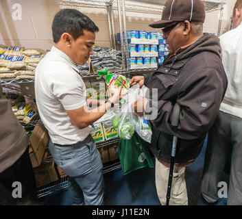 Un missionario Mormone, sinistra, assiste il cliente presso il Catholic Charities Bronx della distribuzione alimentare Center di New York il Giovedì Santo, 13 aprile 2017. Il centro di distribuzione, rifornito con generose donazioni da Goya alimenti e altre società elabora 513,000 libbre di cibo al mese, distribuire direttamente ai bisognosi e attraverso una rete di interfaith gli alimenti riposterie in tutto il Bronx e Upper Manhattan. Catholic Charities sta celebrando il 100 anniversario quest'anno. (© Richard B. Levine) Foto Stock