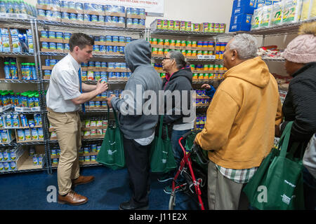 Un missionario mormone assiste un client presso la Catholic Charities Bronx della distribuzione alimentare Center di New York il Giovedì Santo, 13 aprile 2017. Il centro di distribuzione, rifornito con generose donazioni da Goya alimenti e altre società elabora 513,000 libbre di cibo al mese, distribuire direttamente ai bisognosi e attraverso una rete di interfaith gli alimenti riposterie in tutto il Bronx e Upper Manhattan. Catholic Charities sta celebrando il 100 anniversario quest'anno. (© Richard B. Levine) Foto Stock