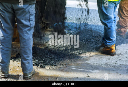 Gli uomini di lavoro duro sulla strada di asfaltatura con pale uomini strada è in costruzione Foto Stock