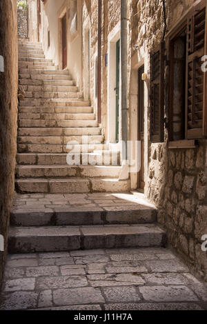 Gradini ripidi cercando una stretta, sun-lit vicoletto a Dubrovnik, Croazia Foto Stock