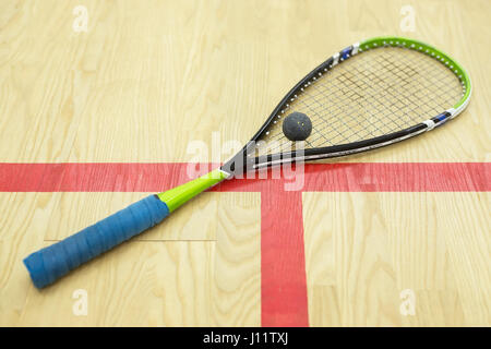 Racchette da squash e la palla sullo sfondo di legno. Raquetball apparecchiature sulla corte vicino alla linea rossa. Foto con il fuoco selettivo Foto Stock