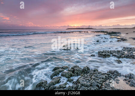 Ultime luci a Capo Trafalgar con le onde che si infrangono sulle rocce e faro di Trafalgar in background, Cadiz, Spagna Foto Stock