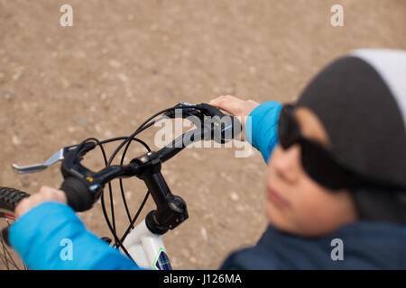 Un ragazzo che indossa gli occhiali da sole si siede su una bicicletta. Foto Stock