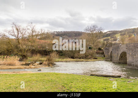 Ponte storico in pietra in un piccolo borgo rurale denominato Oberregenbach vicino a Langenburg in Hohenlohe, una zona della Germania meridionale Foto Stock