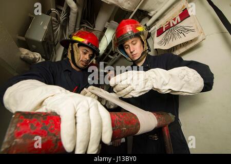 170414-N-KD168-027 Golfo di Aden (14 aprile 2017) dello scafo tecnico di manutenzione Fireman Davontae Partee e macchinista di Mate 2a classe Nicholas Ramsdell patch di un tubo durante la simulazione di una seminatrice di allagamento a bordo dell'assalto anfibio nave USS Bataan (LHD 5). La nave e il suo gruppo pronto sono distribuiti negli Stati Uniti Quinta Flotta area di operazioni a sostegno della sicurezza marittima operazioni destinate a rassicurare gli alleati e partner e preservare la libertà di navigazione e il libero flusso di commercio nella regione. (U.S. Foto di Marina di Massa lo specialista di comunicazione 2a classe Magen F. Reed/rilasciato) Foto Stock