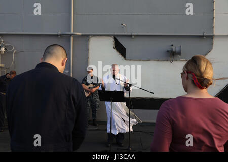 170416-N-UM082-014 Golfo di Aden (16 aprile 2017) il cappellano, Lt. La Cmdr. Jay Kersten conduce una speciale Pasqua Alba servizio sul ponte di volo dell'assalto anfibio nave USS Bataan (LHD 5). La nave e il suo gruppo di pronto, sono distribuiti negli Stati Uniti Quinta Flotta area di operazioni a sostegno della sicurezza marittima operazioni destinate a rassicurare gli alleati e partner e preservare la libertà di navigazione e il libero flusso di commercio nella regione. (U.S. Foto di Marina di Massa lo specialista di comunicazione di terza classe Raymond Minami/rilasciato) Foto Stock