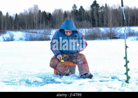 Uomo anziano la pesca in inverno sul lago Foto Stock