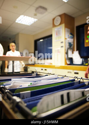 Note paziente con il personale medico a piedi in background su occupato ward nel grande ospedale generale Foto Stock