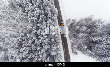 Carrello spazzaneve mantenendo road in difficili condizioni invernali. Vista aerea. Foto Stock