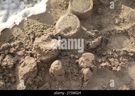 Close up rudimentale castello di sabbia in procinto di essere distrutto da wave Foto Stock