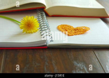 Fiore tarassaco su notebook con il simbolo del cuore di insegnanti felice giorno celebrazione dell'immagine. Fiore giallo fiore primavera messaggio di saluto. Foto Stock