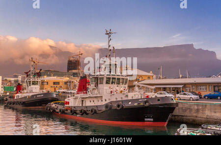 Tirare le barche attraccate al V & A Waterfront con Table Mountain in background come nuvole venire a laminazione , Cape Town , Sud Africa Foto Stock