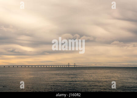 Rocce di grandi dimensioni sulla riva del mare, paesaggi marini e Oresund Bridge in background sulla fredda giornata invernale con drammatica sky Foto Stock