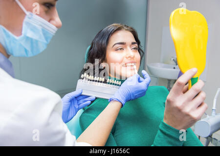 Paziente specchio di contenimento e dentista. Denti grafico a colori. I colori e le sfumature. Foto Stock