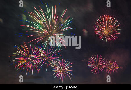 Fuochi d'artificio multicolore con cityscape di notte Foto Stock