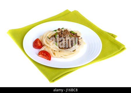 Nido di pasta tagliatelle al ragù su una piastra sul tovagliolo verde isolato su sfondo bianco. Foto Stock