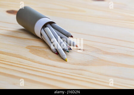 Matite colorate per uscire da una casella grigia su una superficie bianca. Foto Stock