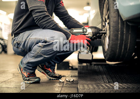 Mechanic uomo che lavora con un pneumatico Foto Stock